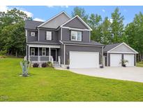Charming two-story home with a well-manicured lawn, two car garage, and inviting front porch with white picket fence at 852 Cokesbury Park Lane Ln, Fuquay Varina, NC 27526