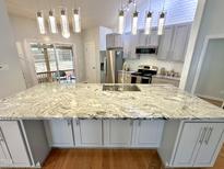 Modern kitchen with white cabinets, stainless steel appliances, large island, and stylish lighting fixtures at 121 Chimney Rise Dr, Cary, NC 27511