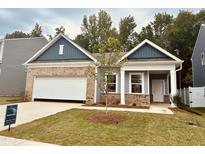 Charming, single-story home boasts a brick and blue facade, complemented by a well-manicured lawn and attached garage at 124 N Keatts Winner Ct, Wilson's Mills, NC 27520