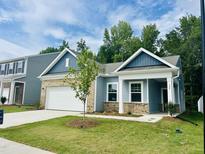 Charming single-Gathering home with a manicured lawn, attached garage, and beautiful blue accents against a bright blue sky at 124 N Keatts Winner Ct, Wilson's Mills, NC 27520
