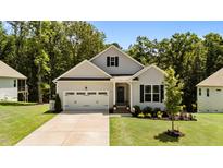 Charming single-Gathering home featuring a two-car garage, well-manicured lawn and lush landscaping at 159 Clear Water Rd, Louisburg, NC 27549