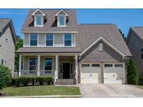 Charming two-story home featuring a brick facade, dormer windows, and a covered front porch at 1600 Drift Falls Ln, Wendell, NC 27591