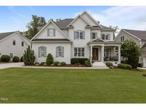 Charming two-story home with white brick, wood trim and gray shutters surrounded by a lush, green lawn at 2077 Amalfi Pl, Apex, NC 27502