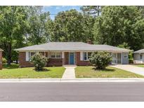 Charming single-story brick home featuring a well-maintained front yard and a bright blue front door at 408 N Stewart St, Clayton, NC 27520