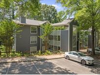 Three-story gray condo building featuring wood trim, a parking lot, and surrounded by mature trees at 4631 Timbermill Ct # 203, Raleigh, NC 27612