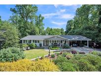 Charming single-story home with a welcoming front porch, lush landscaping, and convenient carport at 582 Wimbleton Dr, Raleigh, NC 27609