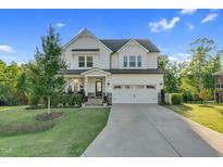 Charming two-story home with a well-manicured lawn and a spacious two car garage and inviting front porch at 6404 Fauvette Lane Ln, Holly Springs, NC 27540