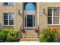 Elegant brick home featuring a front door with sidelights and transom window, framed by lush landscaping at 9603 Clubvalley Way, Raleigh, NC 27617