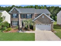 Charming brick two-story home with a two-car garage, manicured lawn, and mature landscaping at 1056 Evening Shade Ave, Rolesville, NC 27571