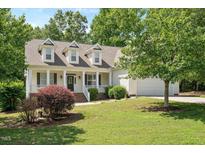 Charming exterior featuring a well-maintained lawn, covered porch, and attached garage at 120 Tanager Farms Dr, Youngsville, NC 27596