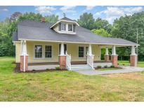 Charming yellow home with a welcoming front porch, brick foundation, and a well-maintained lawn at 1398 Tarboro Rd, Youngsville, NC 27596