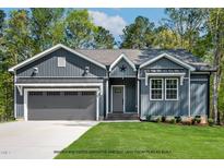 Charming single-story home with gray siding, a two-car garage, and a well-manicured lawn at 154 Buckaroo Dr, Louisburg, NC 27549