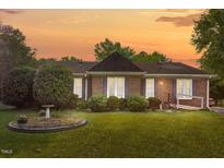 Charming brick home with mature landscaping, a birdbath, and warm sunset hues creating an inviting curb appeal at 1641 Regency Dr, Burlington, NC 27215