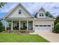 Charming home featuring a covered front porch, a two-car garage, and well-manicured lawn at 18 Heathgreen Dr, Clayton, NC 27527