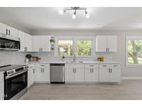 Bright kitchen features white cabinets, stainless steel appliances, light countertops, and a view of the backyard at 2003 Broadway Rd, Sanford, NC 27332
