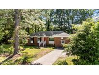 Charming single story brick home featuring a bright red door and mature trees at 208 Essex Rd, Nashville, NC 27856