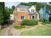 Charming brick home with blue door, landscaped front yard, and mature trees at 2236 The Cir, Raleigh, NC 27608