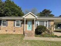 Charming brick home featuring a welcoming turquoise front door and well-maintained landscaping at 305 Briarcliff Dr, Dunn, NC 28334