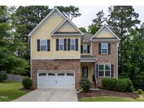 Charming two-story home with stone and yellow shingle exterior and well-manicured lawn at 317 Springhurst Ln, Cary, NC 27511