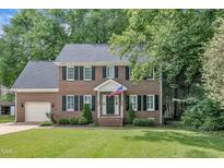 Traditional two-story brick home featuring black shutters, attached garage, and manicured front yard at 418 Old Scarborough Ln, Garner, NC 27529