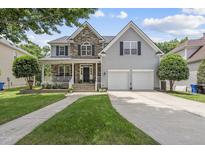 Charming two-story home features a stone facade, inviting front porch, and a well-manicured lawn at 507 Littleport Dr, Rolesville, NC 27571