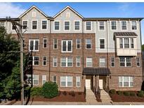 Attractive brick townhome with a covered entryway, manicured landscaping, and gray shingle siding on the upper floors at 531 N Person St # 205, Raleigh, NC 27604