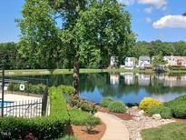 Scenic view of the lake, surrounded by lush landscaping and charming homes at 631 Springfork Dr, Cary, NC 27513