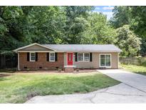 Charming single-story home with a brick facade, a red door, and a well-maintained front lawn at 7216 Carlton Dr, Raleigh, NC 27616
