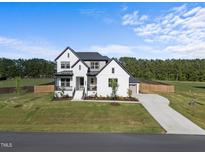 Stunning two-story home featuring a black roof, white brick, manicured lawn and a concrete driveway at 105 Scotland Dr, Youngsville, NC 27596