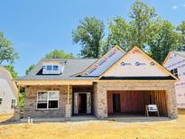 New construction features a brick exterior, attached garage, and unfinished landscaping under a clear blue sky at 1087 Fairhaven Dr # 48, Mebane, NC 27302