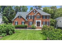 Charming brick home featuring a manicured front lawn, lush landscaping, and classic architectural details at 112 Sterling Ridge Way, Cary, NC 27519