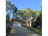 Charming brick and vinyl home with attached garage and well-manicured lawn surrounded by mature trees at 119 Comanche Dr, Louisburg, NC 27549