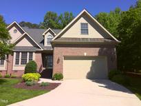 Charming brick home showcasing manicured landscaping, a two-car garage, and a welcoming entrance at 12 Crail Ct, Durham, NC 27712