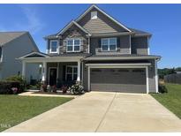 Charming two-story home featuring a two-car garage, stone accents, a welcoming front porch and beautifully landscaped yard at 137 Campaign Dr, Mebane, NC 27302