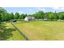 Sprawling property featuring a charming home with a black fence around the land and a lush green yard at 1717 Ormond Rd, Hurdle Mills, NC 27541