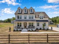 Charming two-story home with black roof, white siding, and a cozy front porch in a serene country setting at 2371 Old Us 421, Lillington, NC 27546