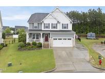 Charming two-story home featuring a white picket fence and a two-car garage with a manicured front yard at 2909 Landon Pines Ct, New Hill, NC 27562