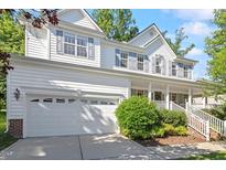 Charming two-story home featuring a two-car garage, covered porch, and white siding with blue shutters at 300 Quarryrock Road Rd, Holly Springs, NC 27540