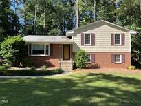 Charming two-story home with red brick and light yellow siding, complemented by lush greenery and a well-manicured lawn at 3205 Broyhill Cir, Raleigh, NC 27604