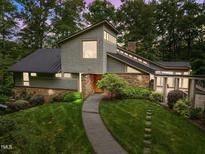 Stylish home featuring stone accents, unique architecture, and a well-manicured lawn with lush landscaping at 343 Lakewood Pointe Dr, Roxboro, NC 27574