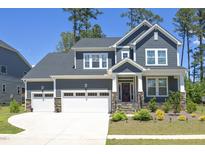 Beautiful two-story home with a three-car garage, stone accents, and a well-manicured lawn at 609 Ramsours Mill Dr, Holly Springs, NC 27540