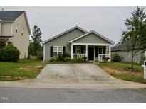 Charming single-story home with a concrete driveway and cozy front porch in a residential neighborhood at 764 Grove Creek Ln, Raleigh, NC 27610
