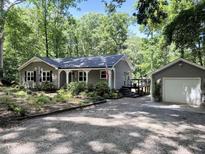 Charming single story home featuring gray siding, white trim, a detached garage and beautiful landscaping at 8620 Glendale Dr, Apex, NC 27539