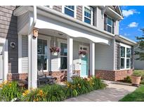 Charming front porch featuring gray rocking chairs, hanging flower baskets, and a quaint blue door at 104 Bollienger Dr, Princeton, NC 27569