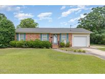Charming brick home featuring a well-maintained lawn, attached garage, and colorful shutters at 1304 Park Ave, Dunn, NC 28334