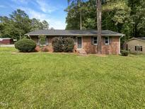 Charming brick ranch-style home featuring well-maintained lawn, shrubs, and a classic design at 1413 Chamblee Rd, Zebulon, NC 27597