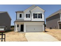 Charming two-story home featuring a two-car garage, sleek black accents, and a 'For Sale' sign in the window at 144 Bruce Dr, Dunn, NC 28334