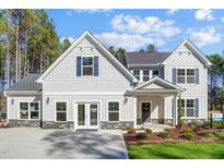 Charming two-story home with gray siding, dark blue shutters, covered porch, and professional landscaping at 16 W Currituck Cir, Garner, NC 27529