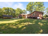 Sprawling backyard showing the brick home and detached garage on a sunny day at 1973 Elon Ossipee Rd, Elon, NC 27244
