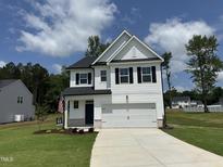 Charming two-story home with a well-manicured lawn and a paved driveway leading to a two-car garage at 224 Wild Turkey Way, Lillington, NC 27546